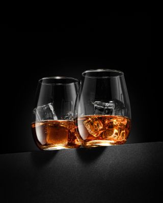 Two whiskey glasses with ice cubes glowing against a sleek black backdrop. Perfect for bar or party themes.