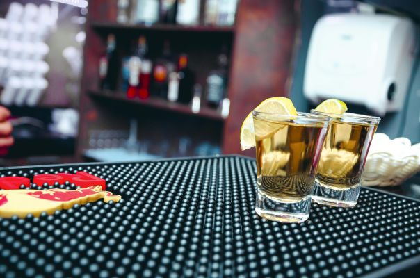 Close-up of tequila shots with lemon slices at a bar, ideal for nightlife scenes.