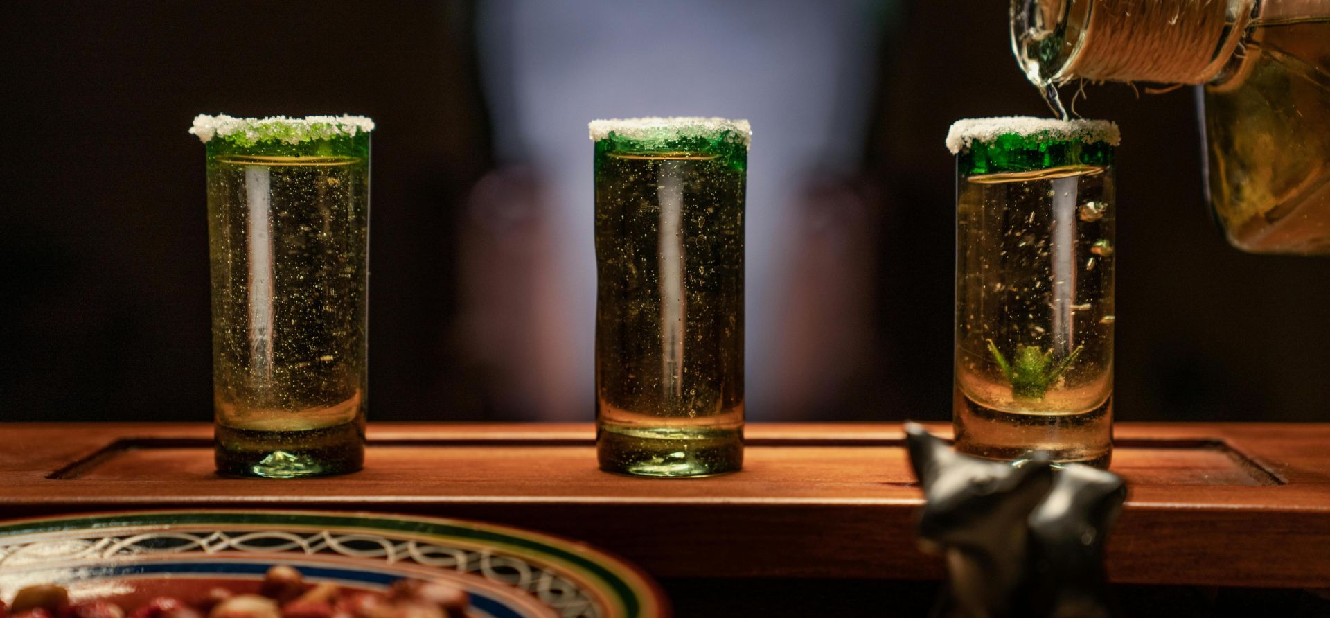 Close-up of tequila shots with salty rims being poured, perfect for a Mexican celebration.